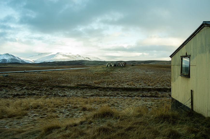 Desolate Icelandic Landscape with Snow-Capped Mountains and Rustic Building