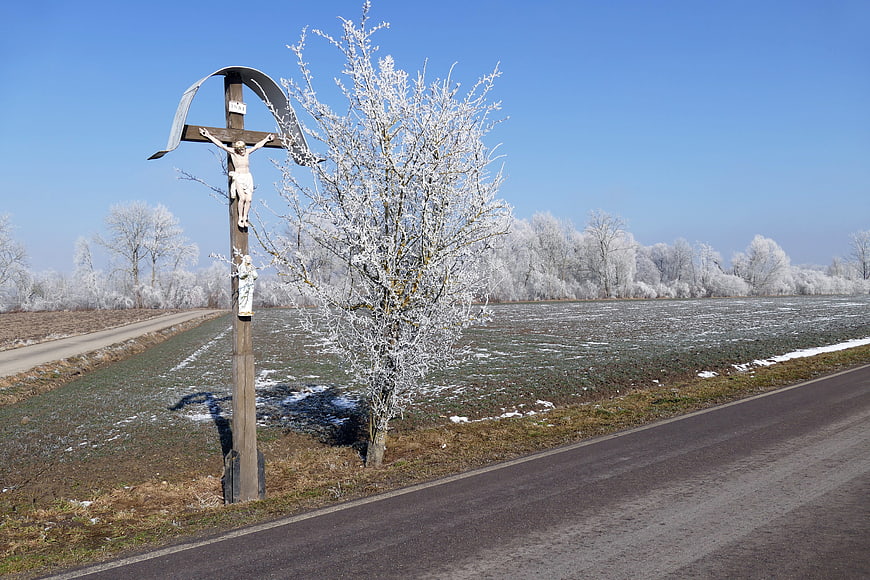 Frosted Wayside Cross on Rural Road in Winter Landscape