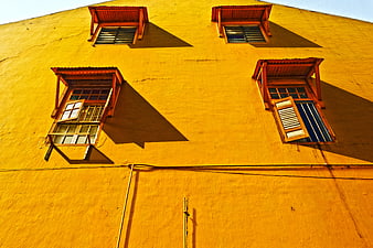 Vibrant yellow building facade with rustic wooden windows