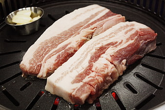 Raw pork belly slices on a Korean BBQ grill