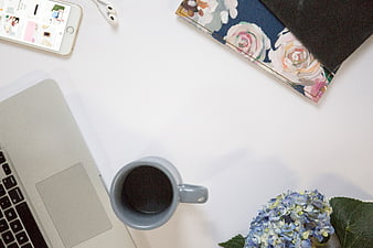 Minimalist workspace flat lay with laptop, coffee, and flowers