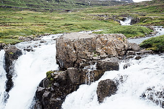 Rushing waterfall cascading over rocks in green valley