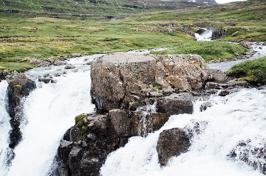 Rushing waterfall cascading over rocks in green valley