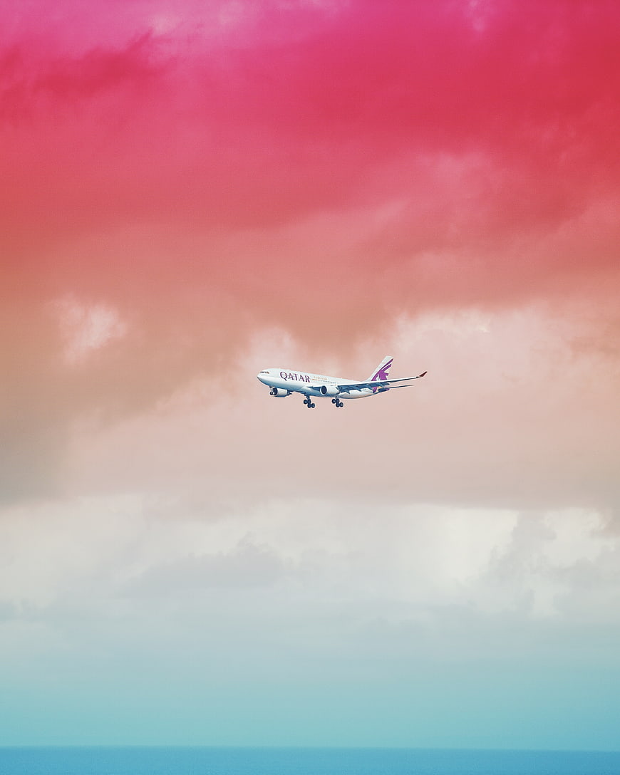 Qatar Airways airplane landing against pink and blue sky