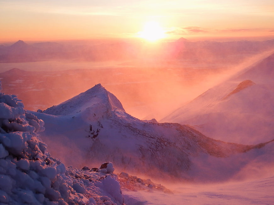 Snowy Mountain Ridge at Sunset with Drifting Snow