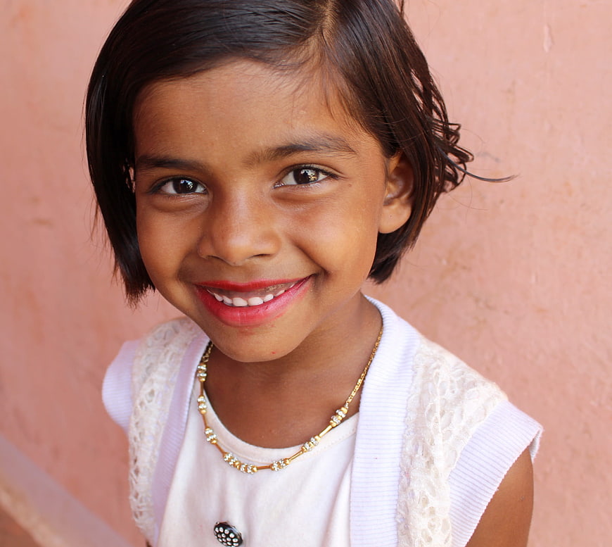 Smiling young girl portrait against pink wall