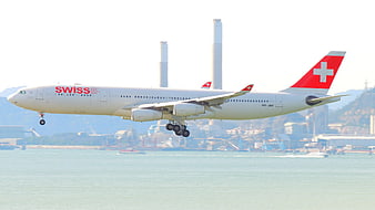 Swiss Air Lines aircraft landing over water with industrial background