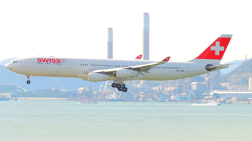 Swiss Air Lines aircraft landing over water with industrial background