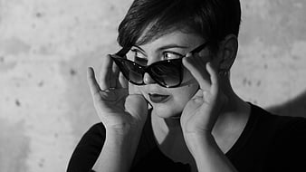 Woman with short hair holding sunglasses in black and white