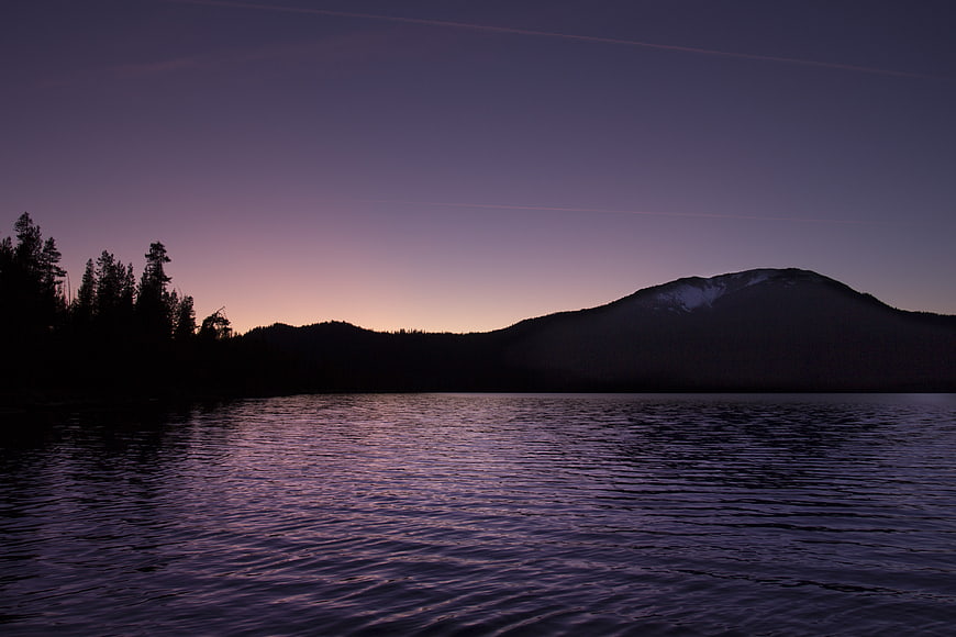 Serene Lake at Dusk with Mountain Silhouette and Purple Sky