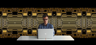 Young man working on laptop with circuit board background