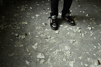 Person Standing on Debris-Covered Hexagonal Tile Floor