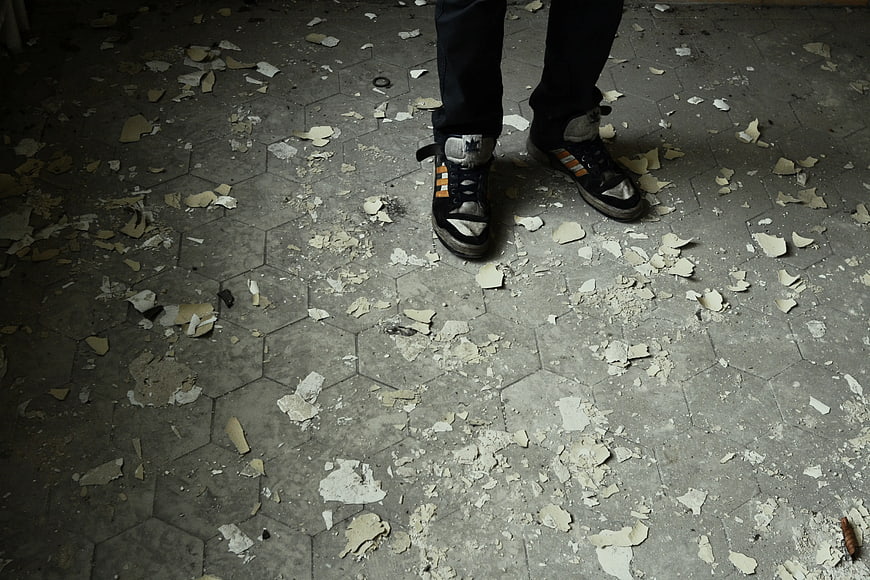Person Standing on Debris-Covered Hexagonal Tile Floor