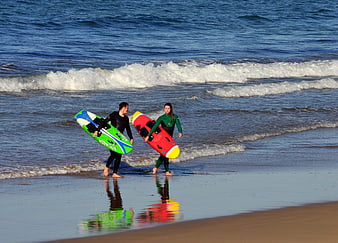 Surfers walking on beach with colorful boards