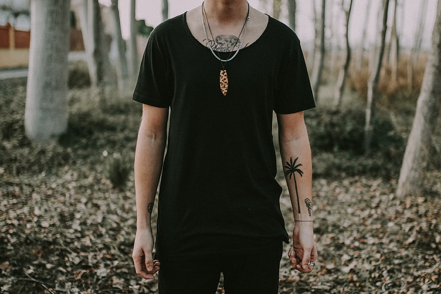 Man with tattoos wearing black t-shirt in autumn forest