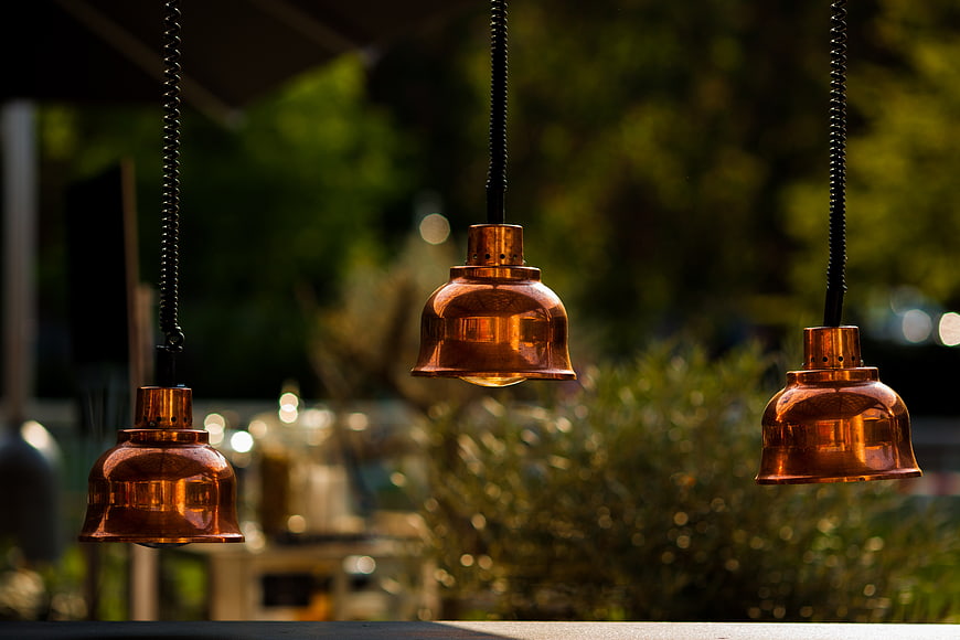 Three Hanging Copper Pendant Lights with Bokeh Background