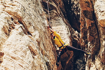 Woman rappelling down steep rocky canyon wall