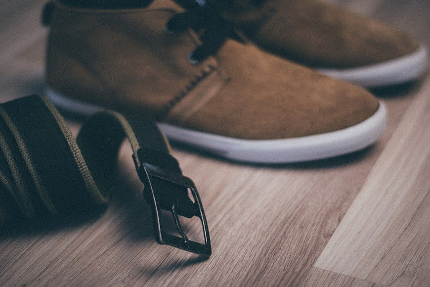 Brown suede boots and black belt on wooden floor