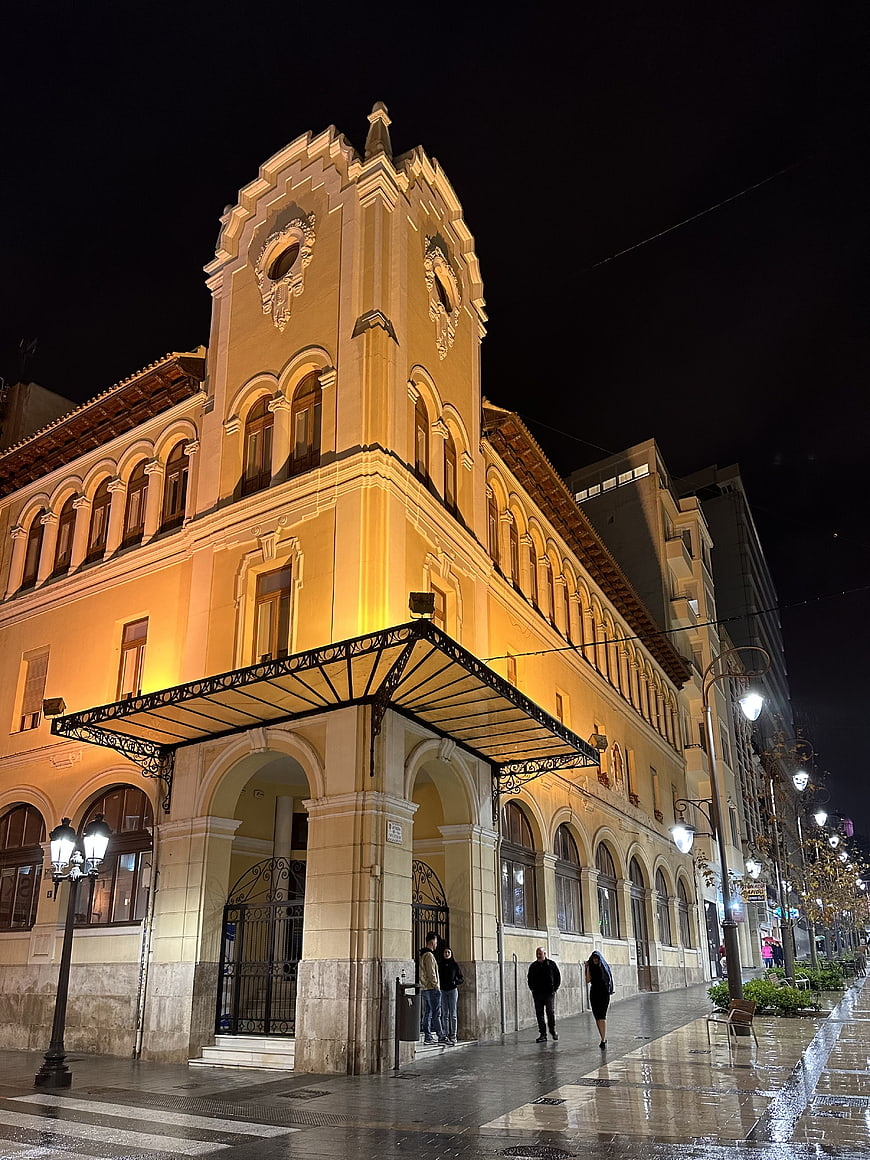 Illuminated historic building facade at night with wet street reflections