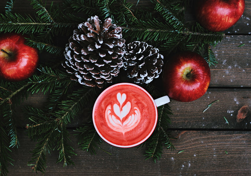 Top view of red latte art with pine branches and apples