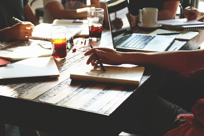 Team meeting with laptops and notebooks on wooden table