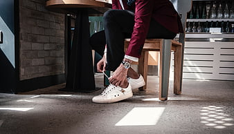Man tying white sneakers in a modern bar interior