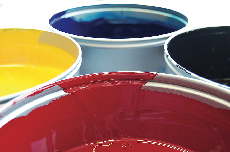 Close-up of red, yellow, blue, and black paint buckets