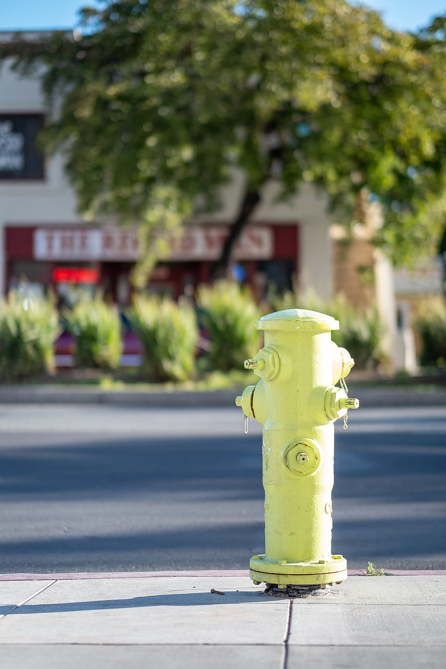 Yellow Fire Hydrant on Sidewalk with Blurred Street Background