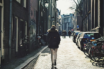 Woman Walking Down Cobblestone Street in European City