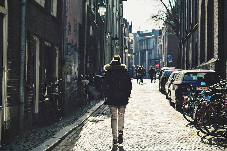 Woman Walking Down Cobblestone Street in European City