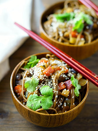 Wooden Bowl of Stir-Fried Noodles with Vegetables and Sesame Seeds