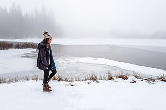 Woman Walking by Frozen Lake in Winter Snow