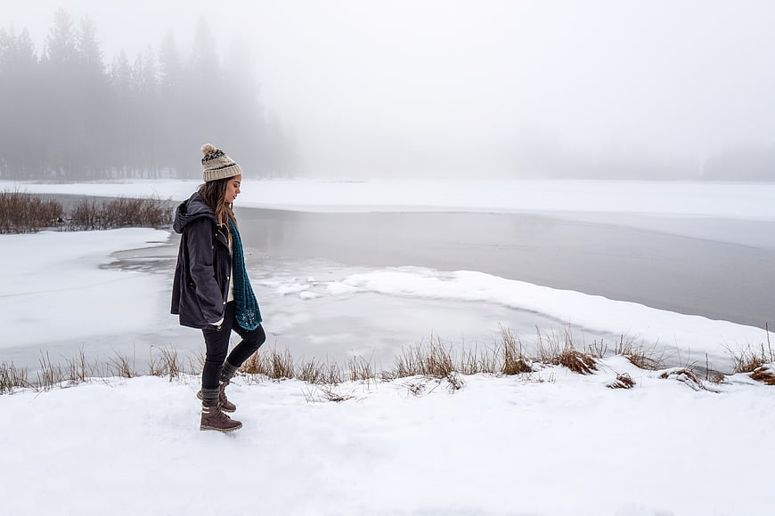 Woman Walking by Frozen Lake in Winter Snow