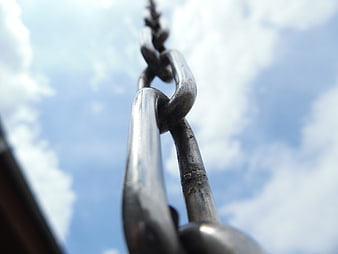 Close-up of metal chain links against blue sky