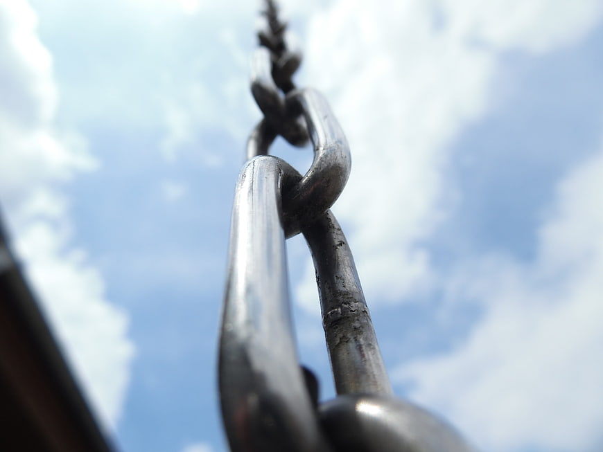 Close-up of metal chain links against blue sky