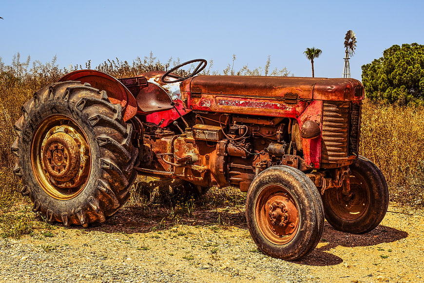 Rusted Vintage Farm Tractor In Rural Countryside Landscape