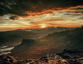 Dramatic sunset over rugged mountain valley with winding river