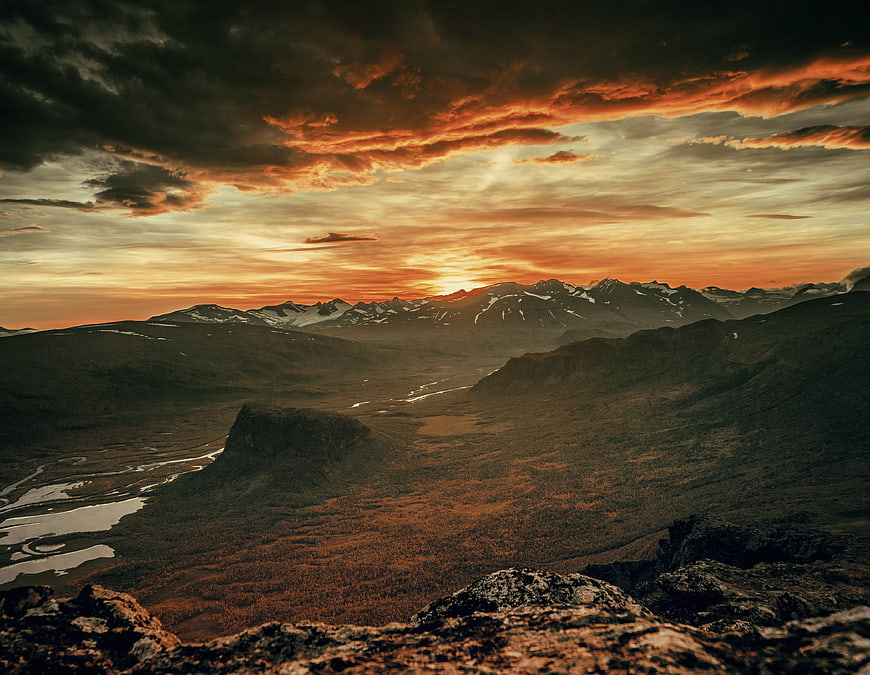 Dramatic sunset over rugged mountain valley with winding river
