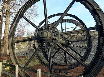 Large vintage industrial water wheel gears against stone wall