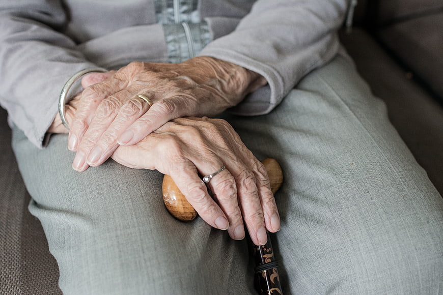Close-up of elderly woman's hands holding a wooden walking stick