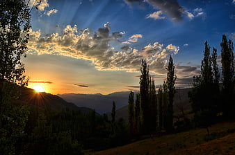 Dramatic Mountain Sunset With Sun Rays And Silhouetted Trees