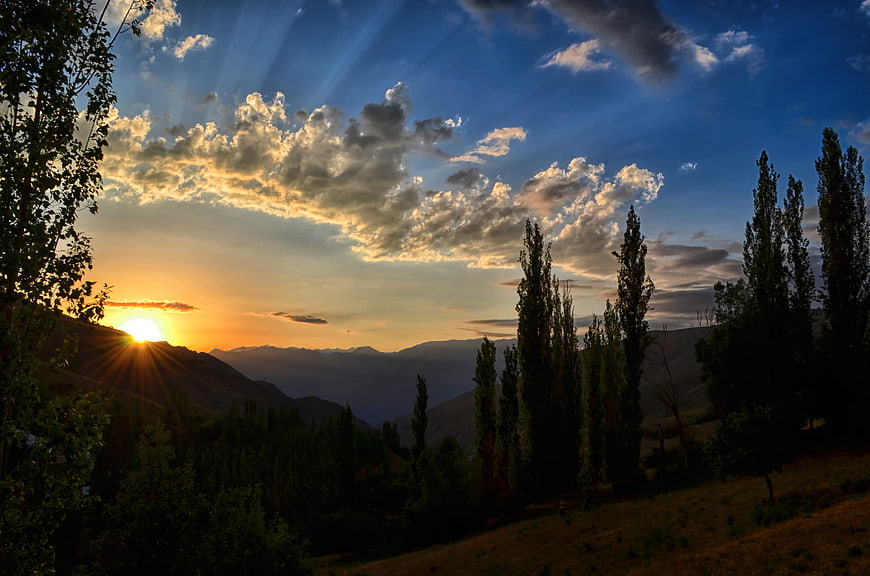 Dramatic Mountain Sunset With Sun Rays And Silhouetted Trees