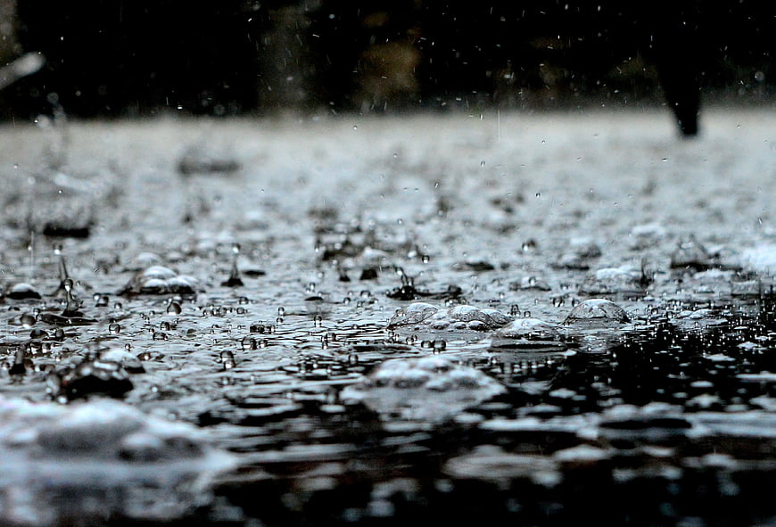 Close-up of raindrops splashing in a puddle on wet pavement
