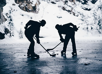 Silhouette of Two Hockey Players Facing Off on Frozen Lake