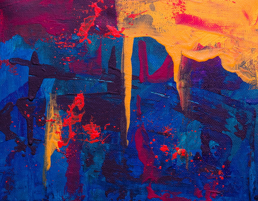 Abstract acrylic painting with vibrant blue, red, and yellow splatters on canvas