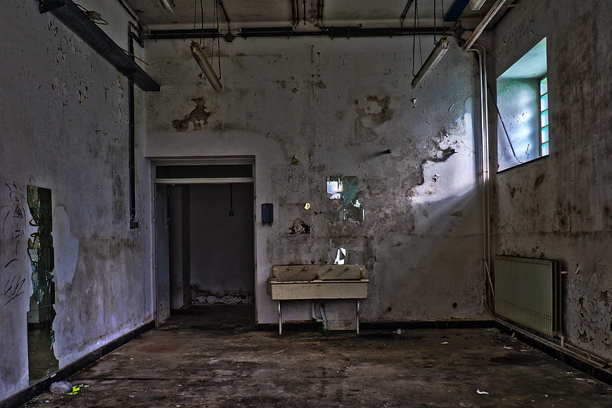 Decaying Interior of Abandoned Hospital Bathroom with Peeling Walls