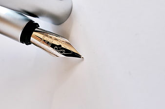 Close-up of gold fountain pen nib on white paper