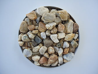 Top-down view of assorted natural river stones in a metal bowl