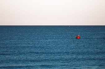 Lone Red Fishing Boat on Calm Blue Ocean Horizon