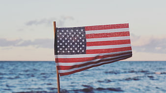 Small American Flag on Beach with Ocean Background